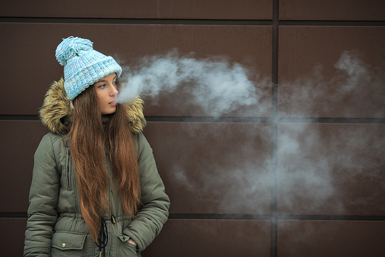 A teen vaping outside in the cold