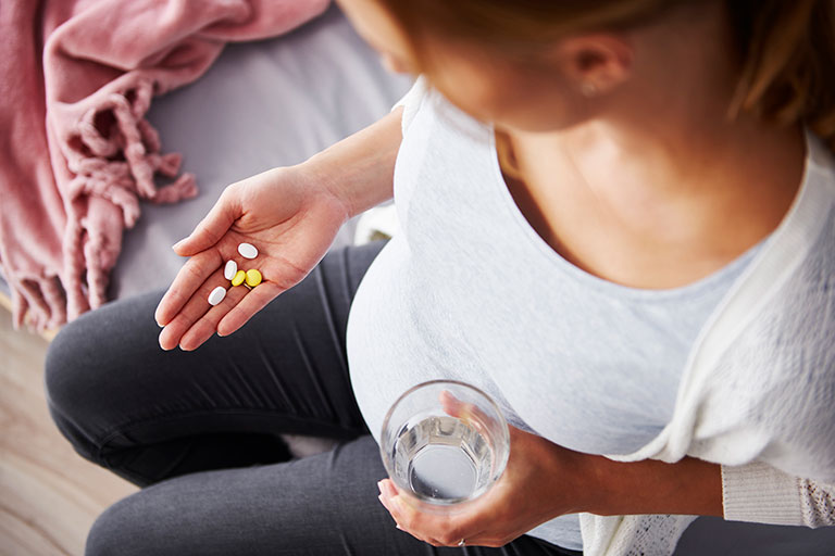 A pregnant woman looking at her medication