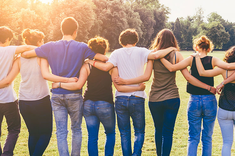 A group of people unifying for an embrace in a field