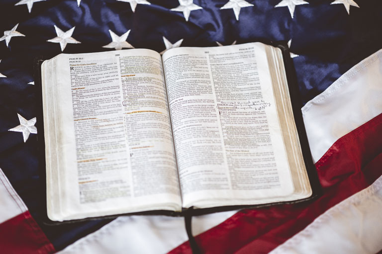 An open bible in front of an American flag